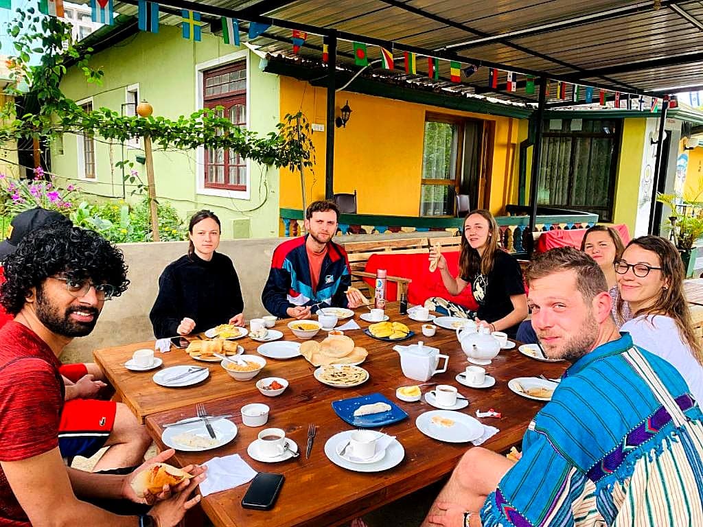 Travellers sharing breakfast together at the long communal table