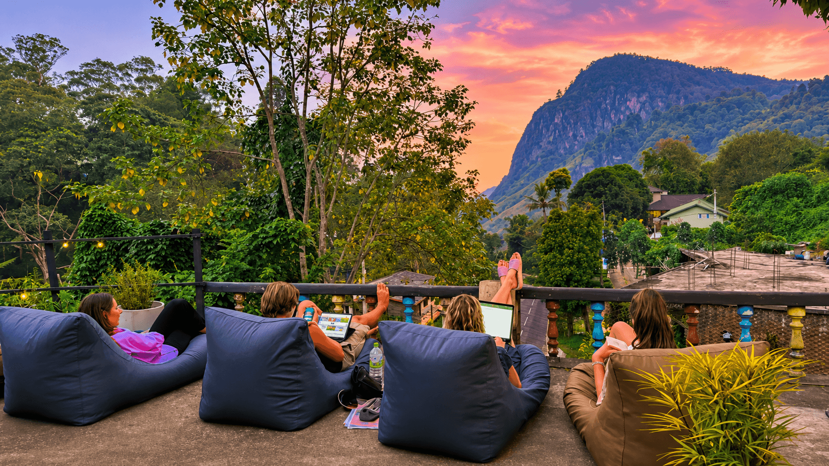 Guests relaxing on bean bags as the sun sets behind Ella Rock