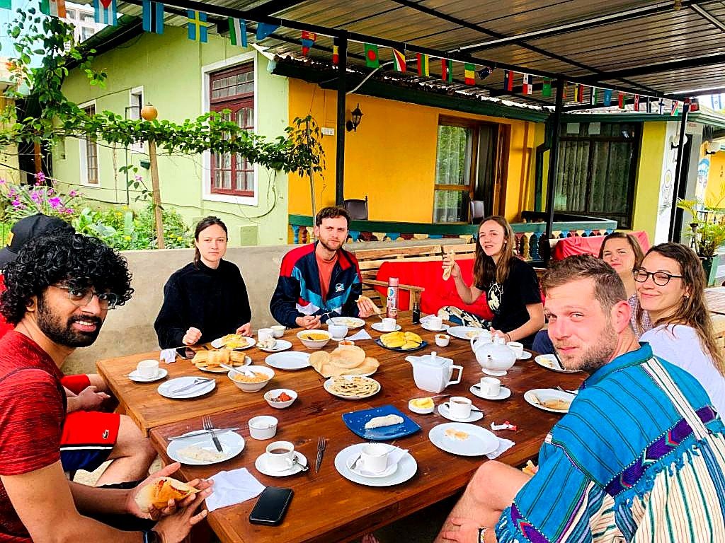 Travellers sharing breakfast together at the long communal table